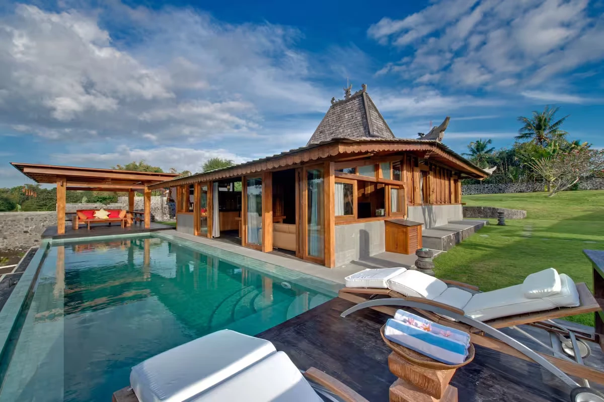 Wooden Javanese house next to a turquoise pool
